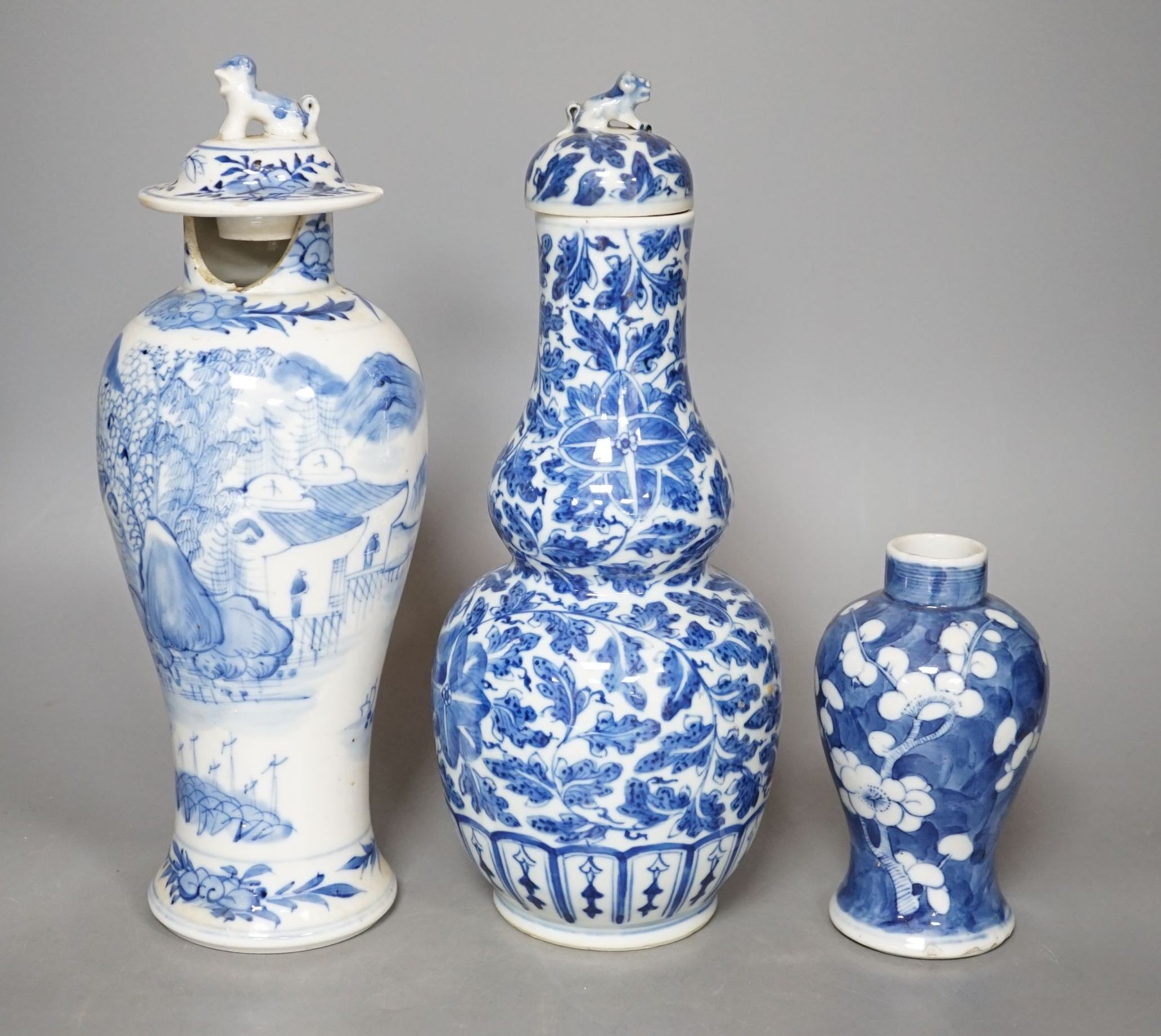 A Chinese double gourd vase and cover, a similar vase and cover and a prunus vase, all 19th century, tallest 28 cms high.